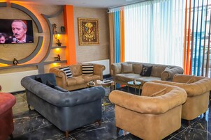 A modern living room with a TV, comfortable sofas, a fireplace, and a large window with curtains.