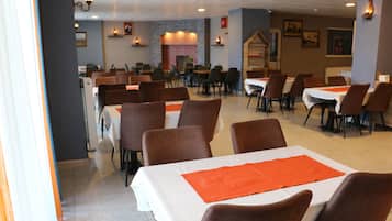 Un restaurante espacioso con varias mesas y sillas, una chimenea y luces fijadas a la pared.