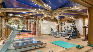 A gym with exercise equipment, a treadmill, and a mirrored wall. - Bright apartment, 2 bedrooms at the foot of the slopes, pool and spa access (Méribel)