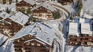 A snow-covered resort with multiple chalet-style buildings, each featuring balconies and a central courtyard. - Bright apartment, 2 bedrooms at the foot of the slopes, pool and spa access (Méribel)