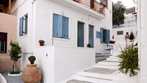 Un bâtiment blanc avec des volets bleus, un escalier et des plantes en pot.