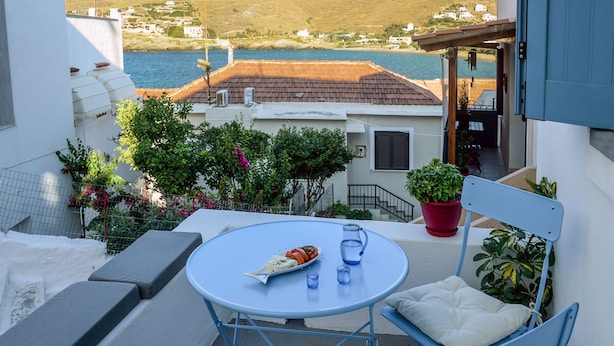 Un balcon avec une table, des chaises et un pot de fleurs.