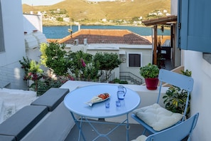 A balcony with a table, chairs, and a potted plant. - Amphoras Apartments (Kea)