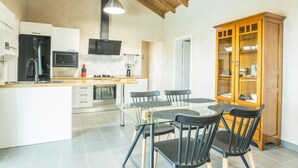 Una cocina moderna con una isla central, mesa de comedor, sillas y un armario de madera.