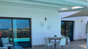 Un patio moderno al aire libre con piscina, zona de estar y vista al océano.