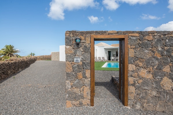 A stone wall with a wooden door leading to a pool area.