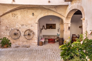 An outdoor courtyard with stone walls, a bench, and potted plants.