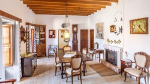 Un comedor con una mesa de madera, sillas, una chimenea y un reloj en la pared.