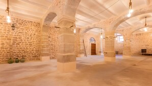 Un interior con paredes de piedra, techos abovedados y lámparas colgantes.