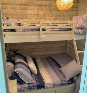 A bunk bed with a wooden headboard and a hanging light fixture above it.