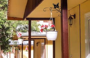A covered porch with hanging flower pots and a butterfly-shaped metal fixture.