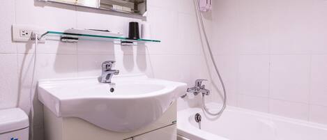 A bathroom with a white sink, mirror, and bathtub.