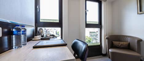 Una habitación moderna con un escritorio de madera, dos ventanas, un sillón de cuero y vistas a la ciudad.