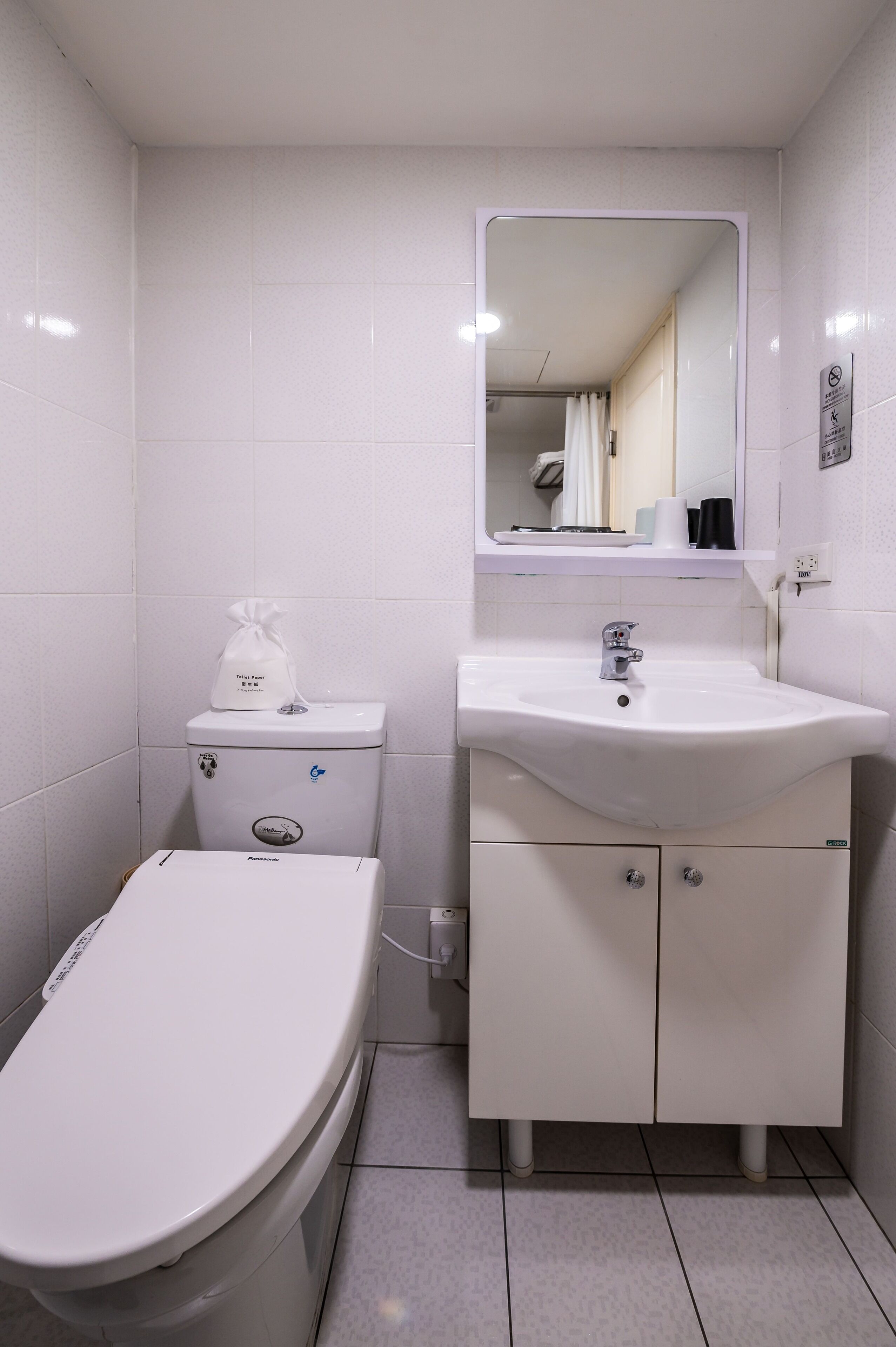 Un baño pequeño y limpio, con inodoro, lavamanos y espejo.
