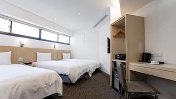 Habitación de hotel con dos camas, un escritorio, una silla, un televisor y una ventana.