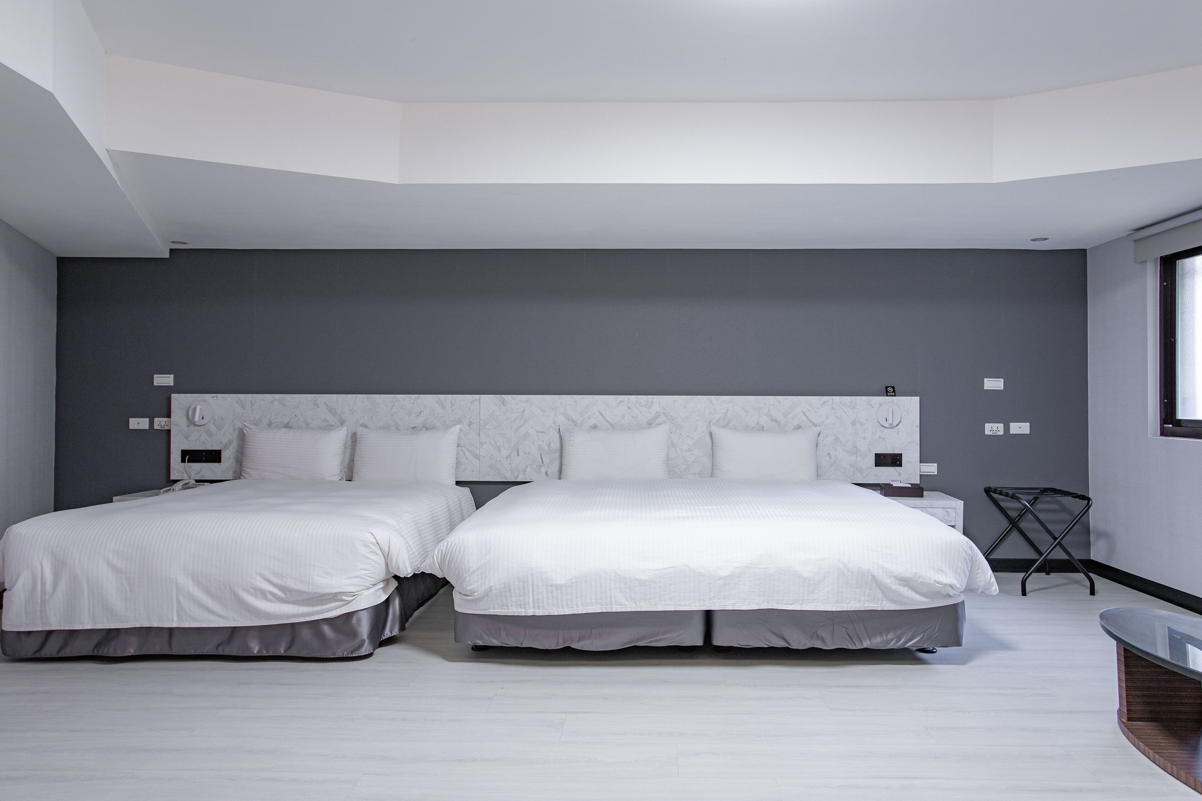 A modern bedroom with two beds, a bedside table, and a chair.