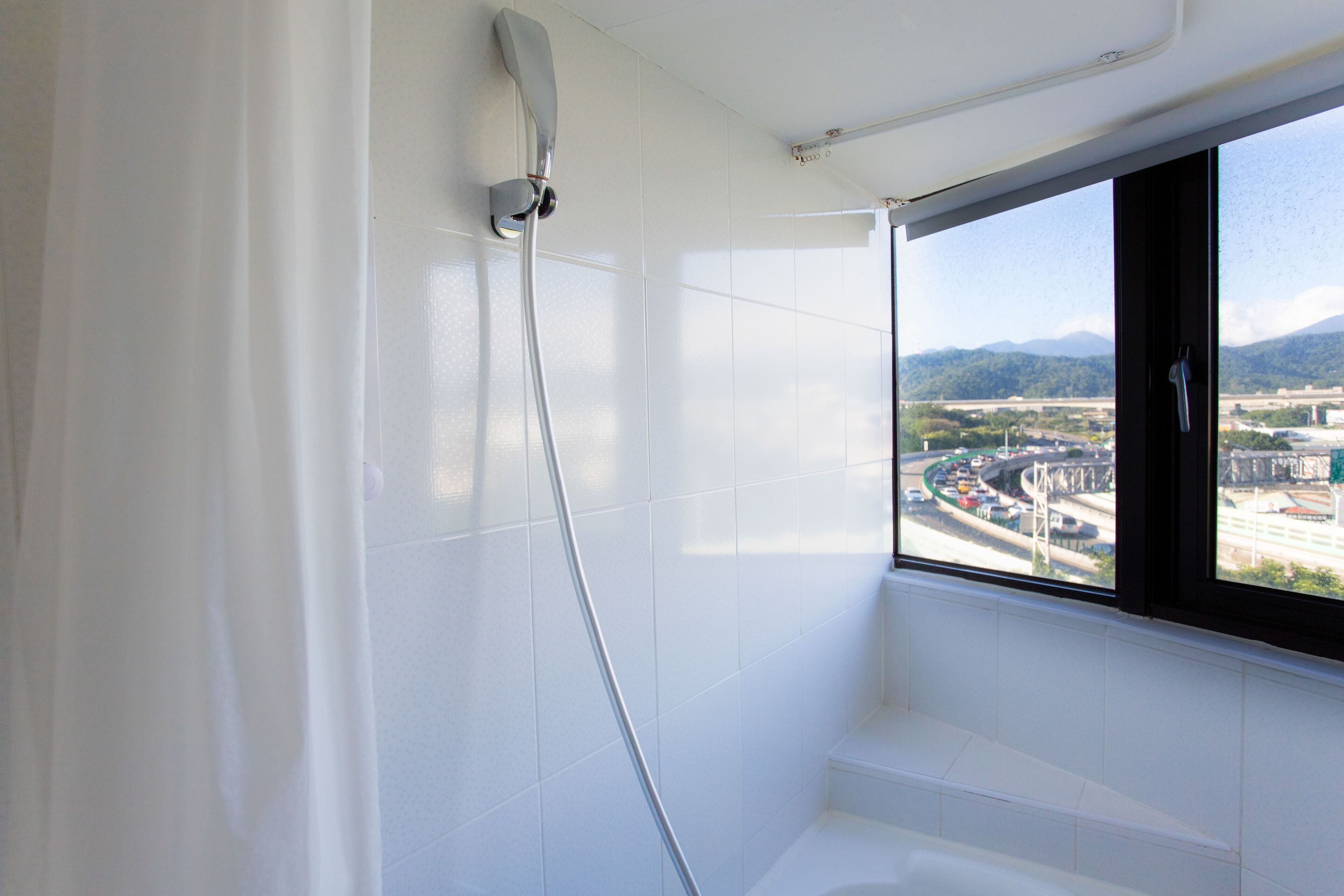 Un baño con bañera, ducha y ventana con vista a la ciudad.