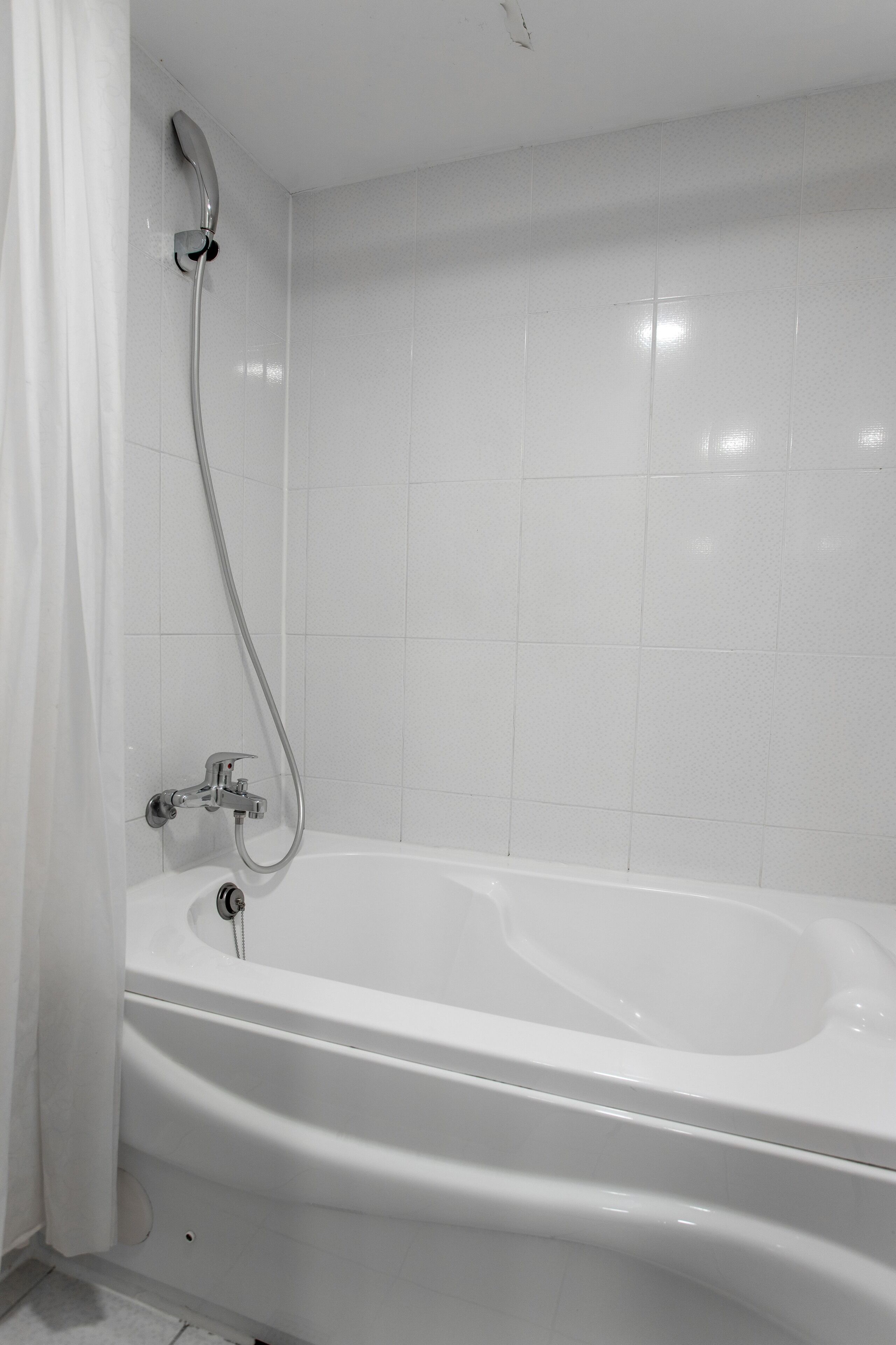 A modern bathroom with a white bathtub, a shower head, and a curtain.