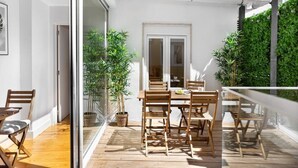 Un patio exterior con muebles de madera y plantas en macetas.