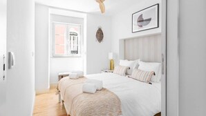 Habitación de hotel moderna con una cama grande, ventilador de techo, ventana con vistas y un cuadro enmarcado en la pared.
