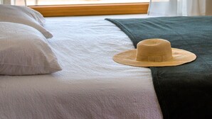 Een bed met uitzicht op een wateroppervlak door een raam.