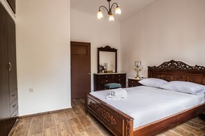 A bedroom with a wooden bed, a dresser, a mirror, and a nightstand. - Casa Del Fantino (Chania)