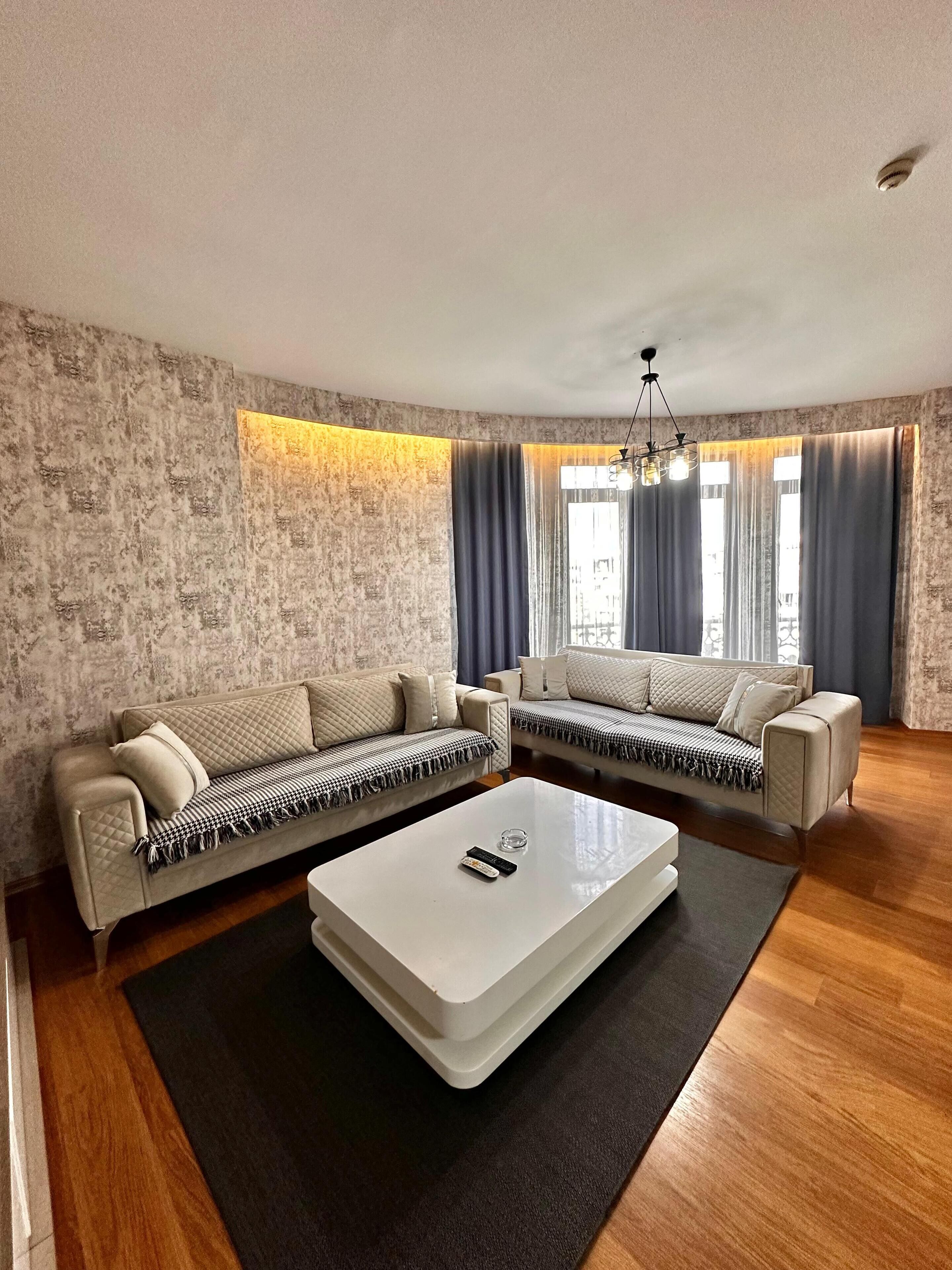 A modern living room with a sectional sofa, a coffee table, and a patterned wall.