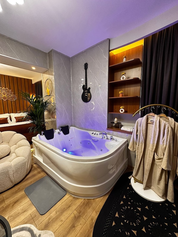Un baño moderno con una bañera independiente, un tocador de madera y un perchero para toallas.