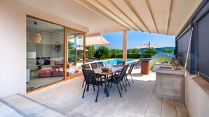 Un patio con mesa y sillas, piscina y puerta de cristal que da a un espacio interior.