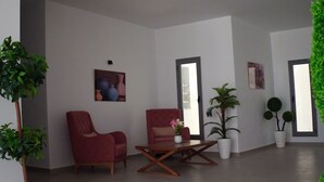 A spacious living area with two red armchairs, a wooden coffee table, and a potted plant. - Hotel Mizwar Djerba (Houmt Souk)