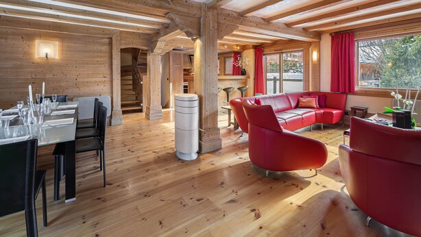 Un interior de madera con comedor, sofá de cuero rojo y una escalera.