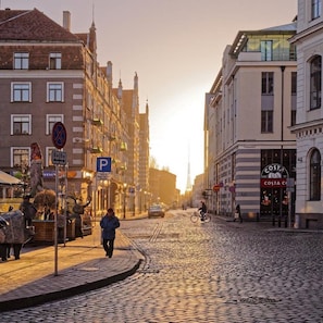 A cobblestone street in a European city with historic buildings, a café, and a Costa Coffee.