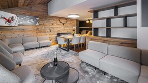 A modern living room with a wooden ceiling, a dining area with a table and chairs, and a built-in bookshelf. - Beautiful apartment in Courchevel with parking 300m from slopes (Courchevel 1550)