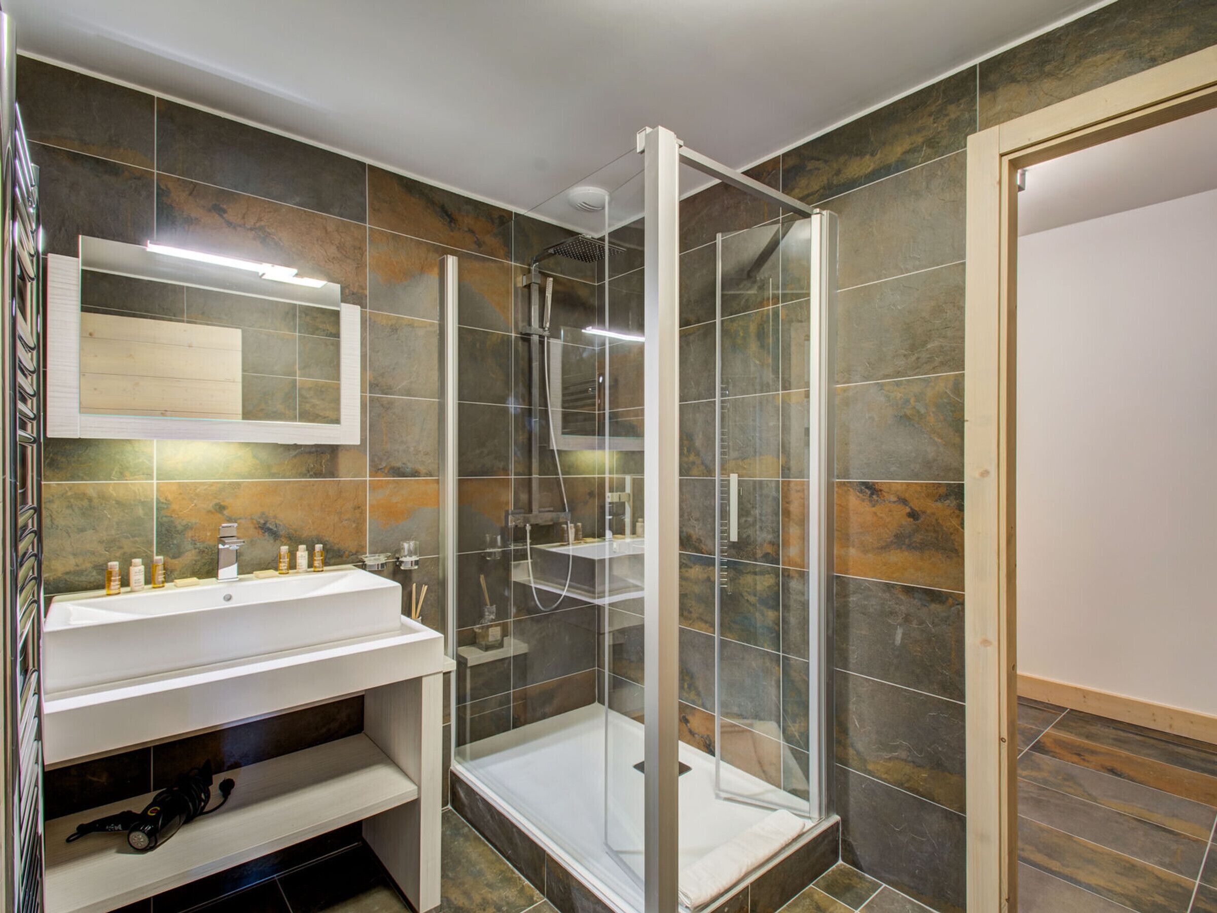 Une salle de bain moderne avec une douche à parois de verre, un meuble-lavabo avec un miroir et un évier.