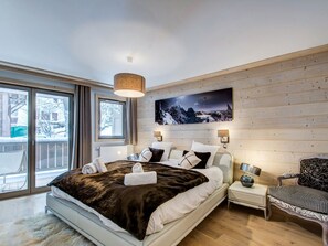 Une chambre à coucher moderne avec un grand lit, un mur en bois, un tableau et une vue sur l’extérieur.