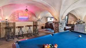 A pool table with billiard balls, a bar area with stools, a television displaying a hockey game, and a cozy seating area with a stone wall. - Modern chalet in Méribel, 5 bedrooms, jacuzzi, near cable car (Méribel)