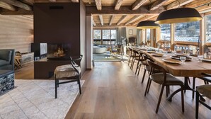 A spacious living area with a fireplace, wooden beams, and a large dining table set for six. - Modern chalet in Méribel, 5 bedrooms, jacuzzi, near cable car (Méribel)