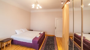 A bedroom with a bed, a bench, a mirror, and a door.