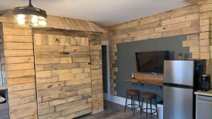 Eine Küche mit Holzwänden, einem Edelstahlkühlschrank und zwei Barhocker.
