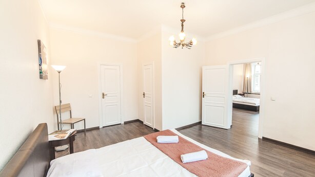 Une chambre d’hôtel avec un lit, une chaise, un bureau, une lampe et un lustre.
