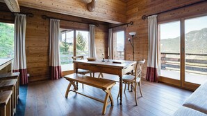 A wooden cabin interior with a dining table, chairs, and a mounted animal head. - Authentic Swiss Spa Chalet Hot Tub & Sauna (Riddes)