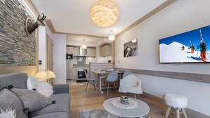 A modern living room with a grey sofa, a round coffee table, and a stone wall with a mounted animal head. - Family apartment in central Courchevel with parking and wifi (Courchevel 1550)