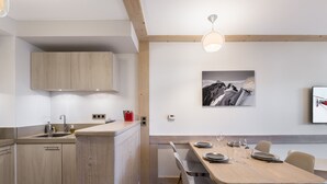 A modern kitchen with wooden cabinets, a built-in island, and a dining area with a wooden table and chairs. - Family apartment in central Courchevel with parking and wifi (Courchevel 1550)