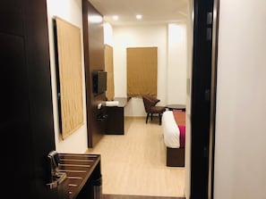 Una habitación de hotel con escritorio, silla, cama y una mesita.