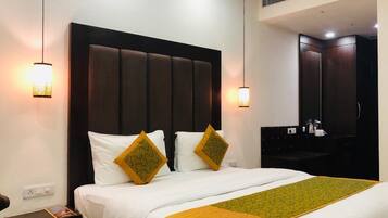 A hotel room with a large bed, two bedside lamps, a dark headboard, and a small table with a magazine.