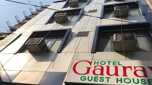 Un hôtel appelé « Gaurav Guest House », doté de plusieurs étages, de systèmes de climatisation et d’une enseigne.