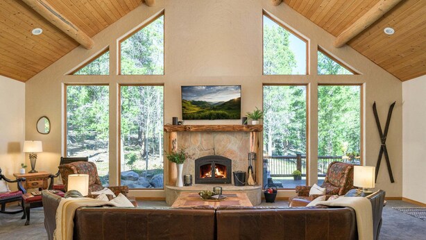 Una sala de estar acogedora con chimenea de piedra, ventanas amplias y vistas al exterior.