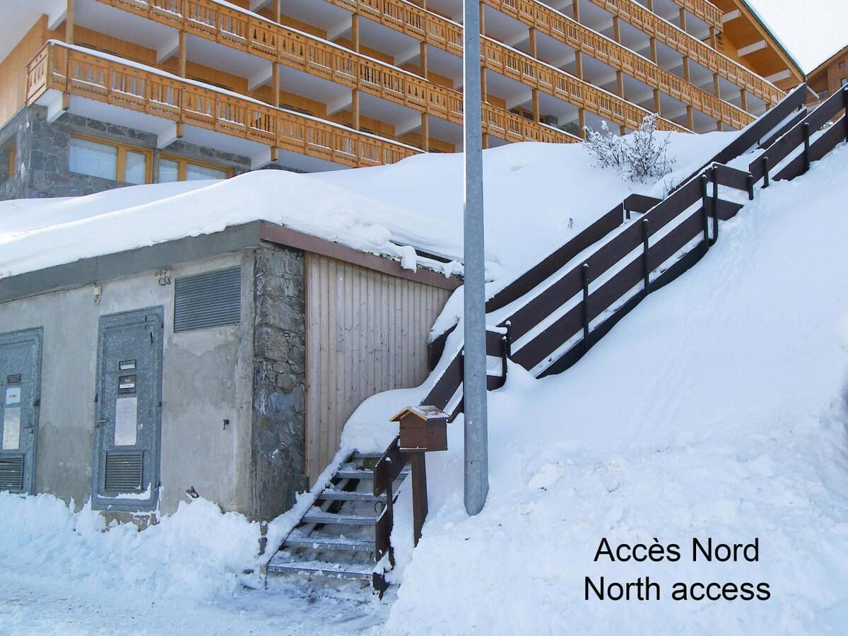 A snowy staircase leading to a building with a wooden balcony.