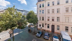 Straßenansicht mit einer Reihe mehrstöckiger Gebäude, geparkten Autos und einem Fahrrad.