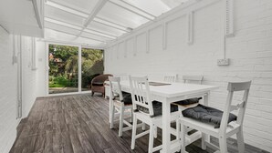 Ein helles Interieur mit Holzboden, weißen Wänden und einer Glastür zum Außenbereich.